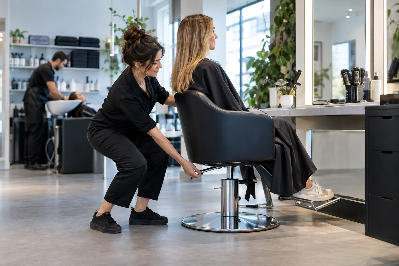 Une coiffeuse ajuste la hauteur d’un fauteuil afin d’adapter son poste de travail